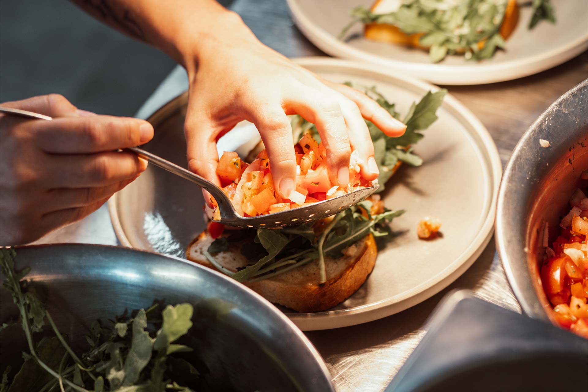 Hand richtet ein Brot mit frischen Zutaten auf einem Teller an.