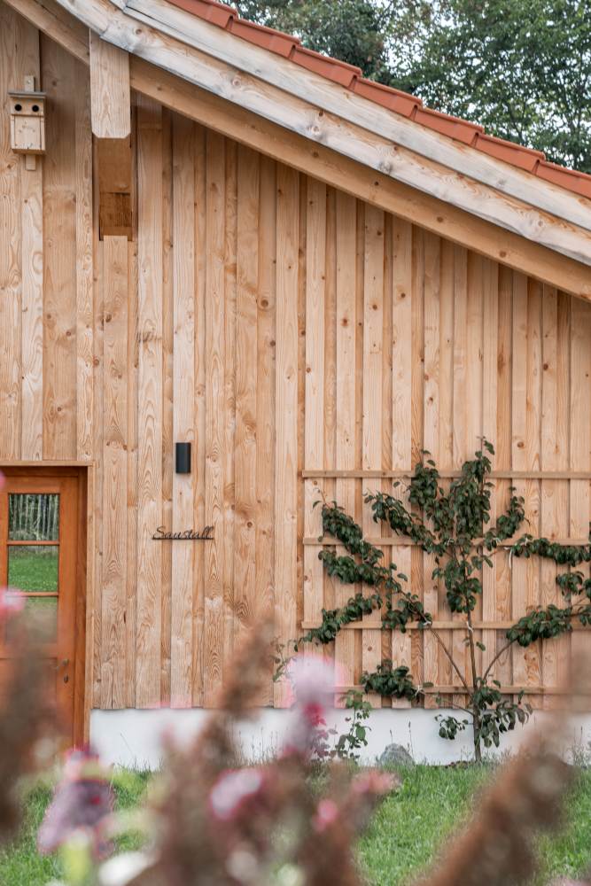 Außenansicht der Denkwerkstatt am Mächlerhof mit Holzfassade und Kletterpflanzen.
