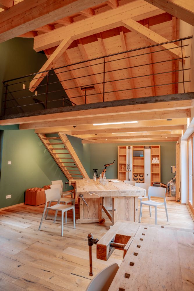 Innenraum der Denkwerkstatt am Mächlerhof mit Holzbalkendecke, Tisch, Stühlen und Empore.